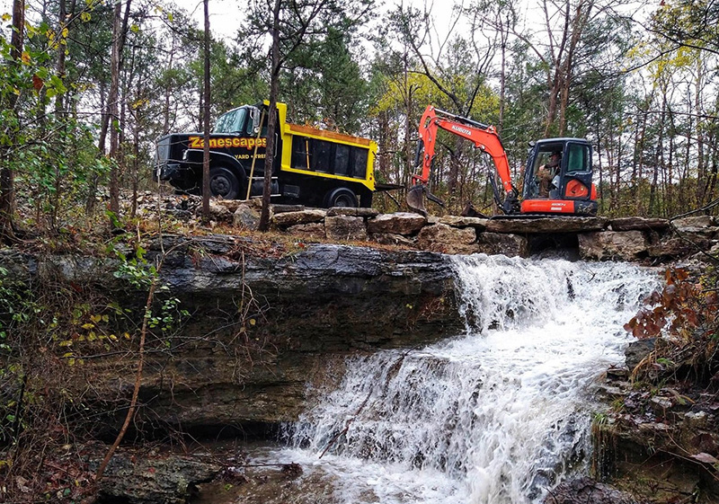 two heavy duty excavation vehicles working on rerouting a creek for irrigation